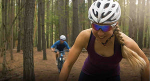A young woman and man couple mountain biking and enjoying themselves riding a trail through the woods.